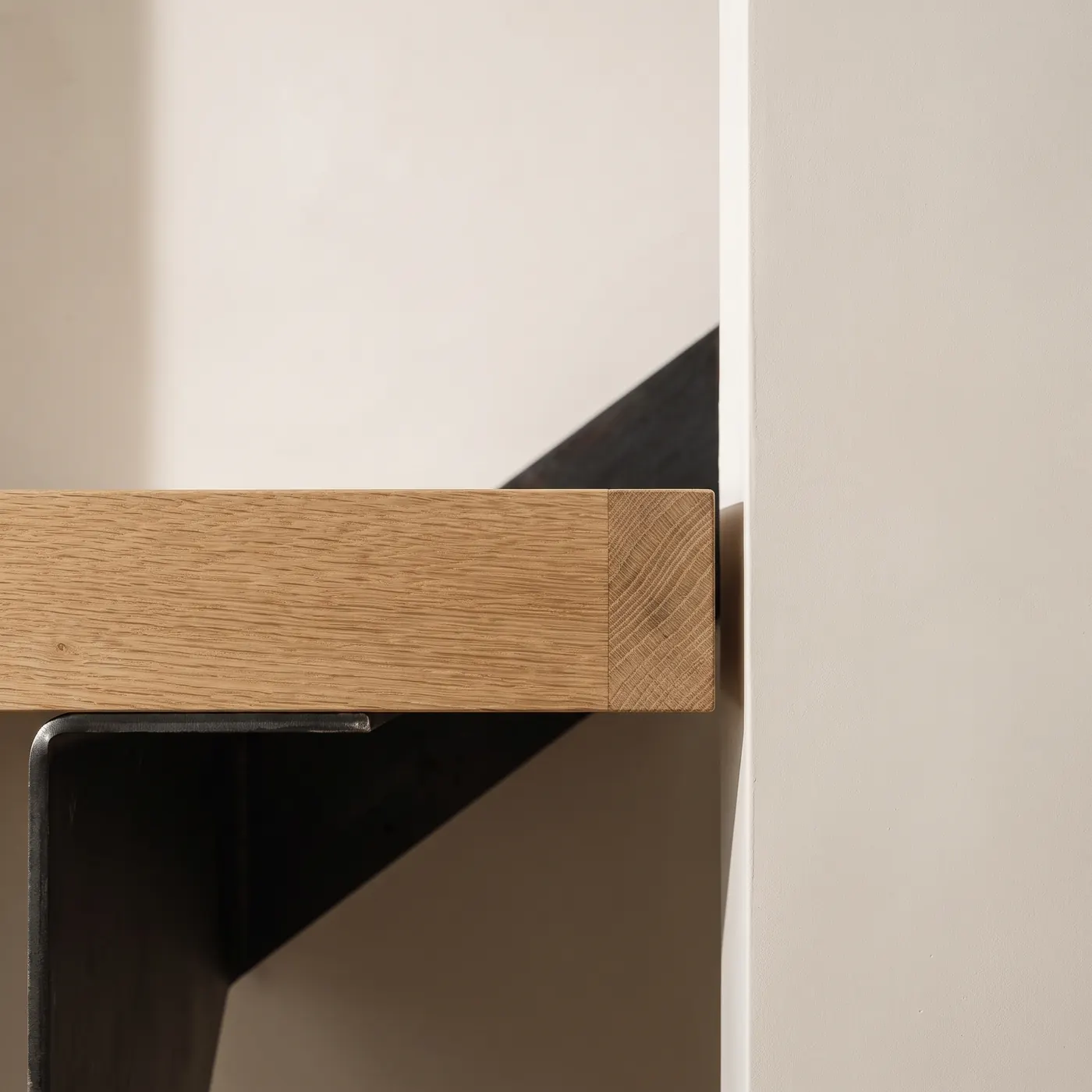 The same junction as built: the white-oak tread stopping a shadow gap short of the lime plaster, the blackened steel bracket beneath it.
